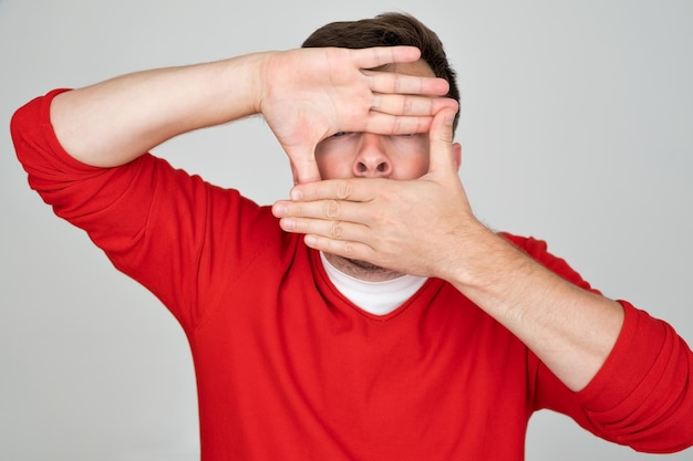 Foto tímido hombre caucásico escondiendo su rostro tratando de permanecer en el anonimato