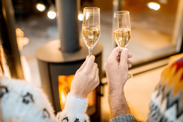 Tinir copos com espumante para celebrar as férias de inverno em casa com lareira