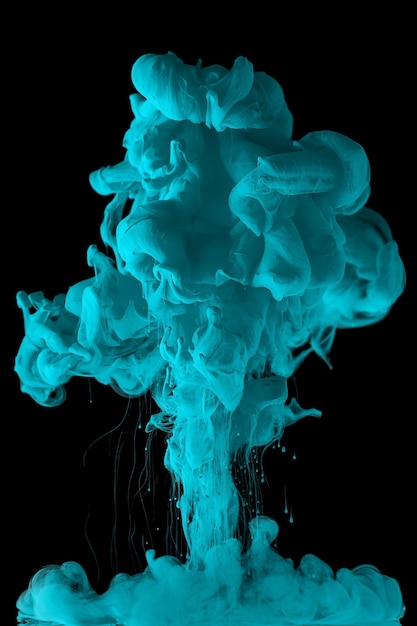 La tinta acrílica en agua forma un patrón de humo abstracto aislado sobre fondo negro