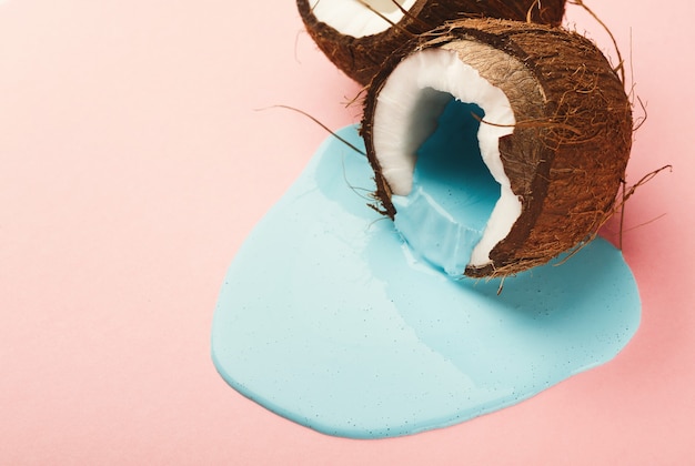 Tinta azul fluindo de coco meio na mesa-de-rosa. Fundo criativo com espaço de cópia, design arrojado para pôster ou impressão de roupas