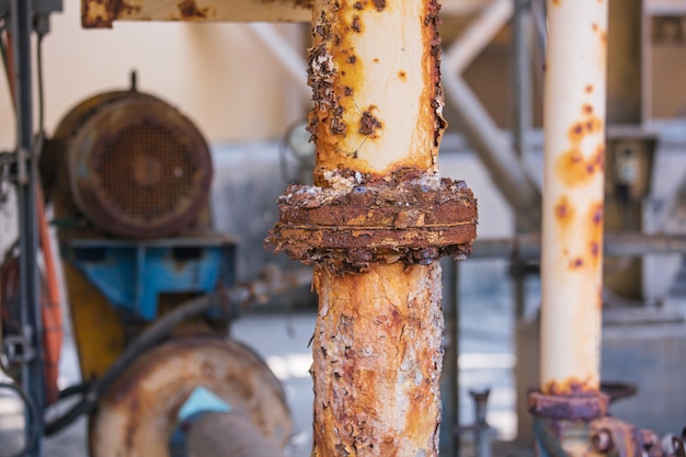 Tinta danificada por ferrugem e flange de corrosão e porca de parafuso no dreno de tubulação industrial.