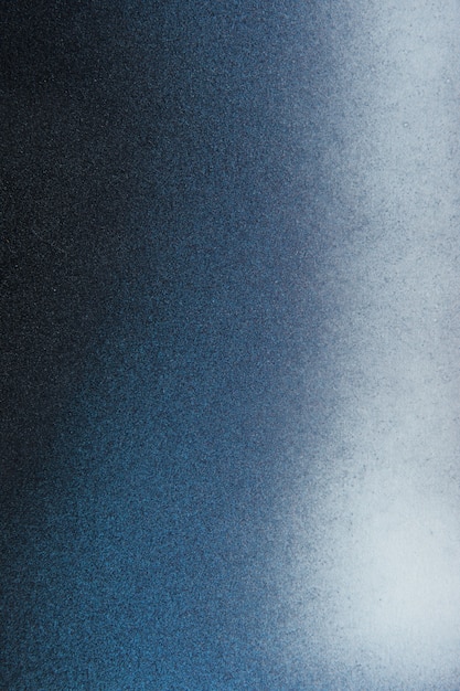 Tinta spray preto e branco em um fundo de papel de cor azul