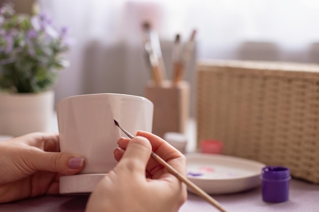 Tintas femininas com pincel em uma panela de cerâmica branca