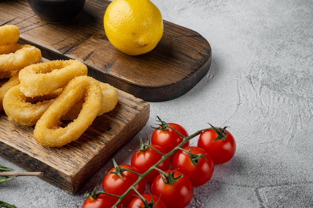 Tintenfischringe oder Zwiebeln im Teig Snack zum Bier auf Servierbrett auf grauem Steintischhintergrund mit Kopierplatz für Text