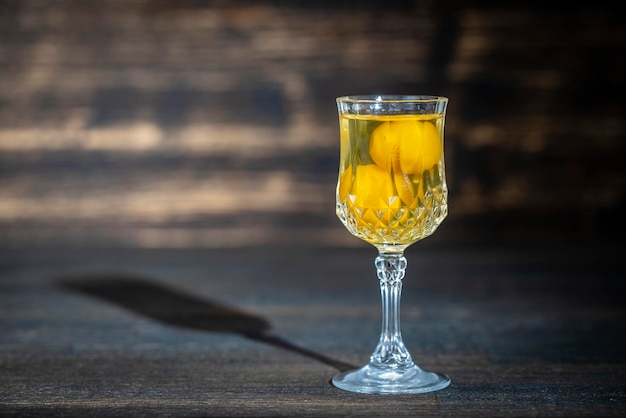 Tintura casera de cristal de vino de ciruela cereza amarilla sobre fondo de madera Ucrania cerrar