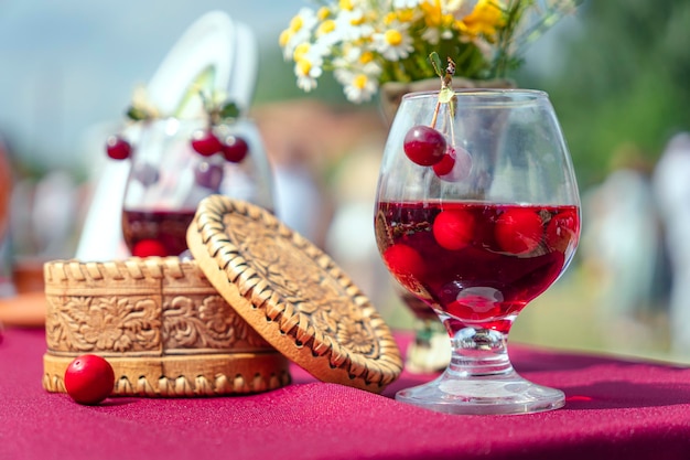 Tintura de cereza dulce en un vaso con bayas sobre la mesa y caja de madera Bebida Nacional Alcohólica