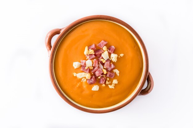 Típica crema de salmorejo español con jamón y huevo aislado en blanco