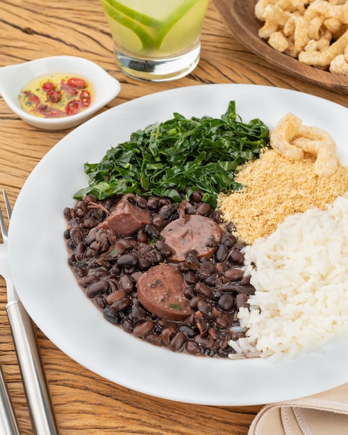 Típica feijoada brasileira com arroz pimenta farofa kale caipirinha e torresmo