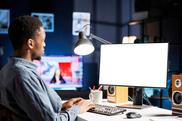 Un tipo afroamericano mira la pantalla blanca en el monitor
