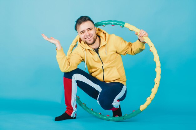 un tipo alegre con una blusa amarilla con un hula hoop muestra un gusto en un fondo azul