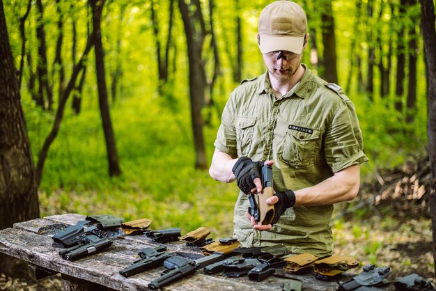 Un tipo en el bosque prueba sus armas para disparar deportes.