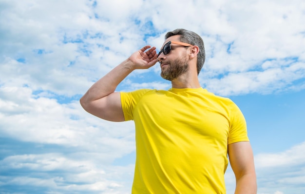 tipo con camisa amarilla y gafas de sol al aire libre en el fondo del cielo