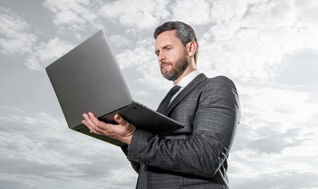 Tipo de homem freelancer no laptop no fundo do céu Homem freelancer com laptop ao ar livre