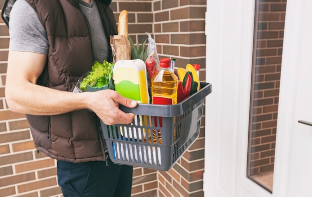 El tipo entrega la canasta llena de víveres a la puerta de la casa. Las compras en línea.