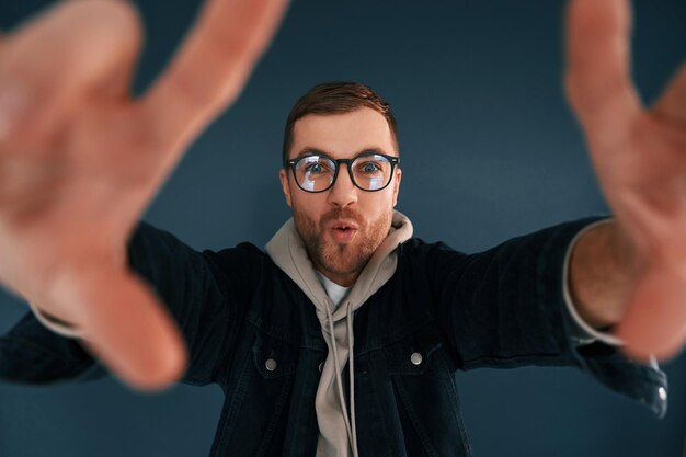 Foto el tipo está fingiendo que él está haciendo una sesión de fotos el hombre guapo está en el estudio contra un fondo azul