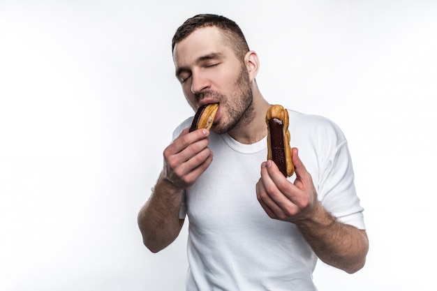 El tipo fuerte está de pie y comiendo éclair