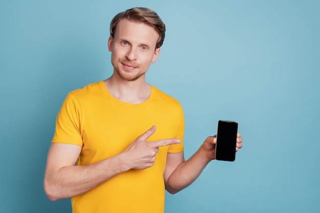 Tipo positivo mantenga teléfono indica dedo pantalla táctil en blanco usar ropa casual aislado sobre fondo turquesa