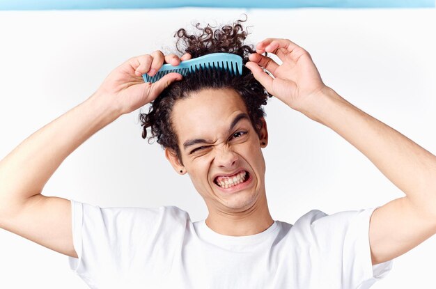 El tipo rizado se metió el peine en el cabello emociones fondo claro foto de alta calidad