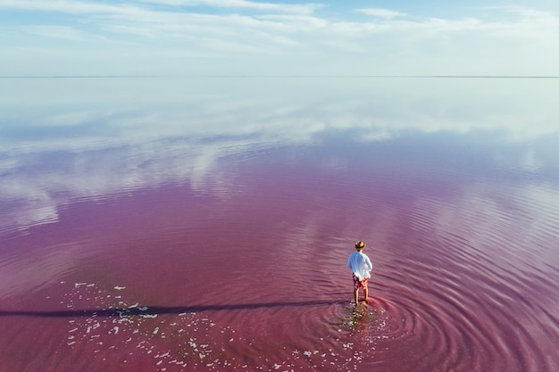 Un tipo con ropa informal da un paseo por las aguas poco profundas de color rosa y púrpura