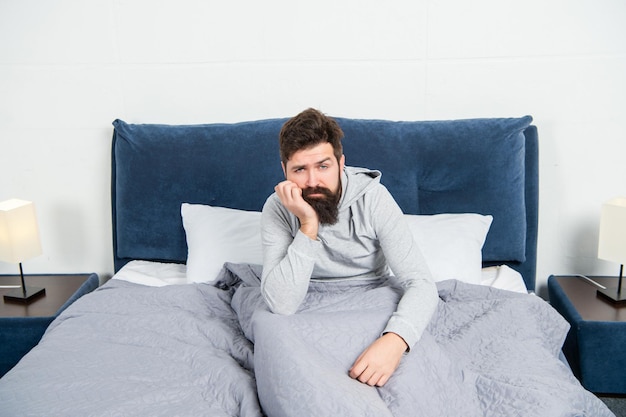 Un tipo somnoliento se siente somnoliento estando en la cama despierto después de dormir por la mañana