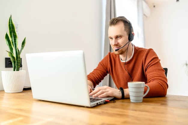 El tipo usa auriculares de manos libres para trabajar desde casa.
