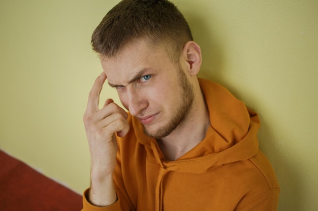 Un tipo vestido de naranja con ojos azules mira con desprecio.