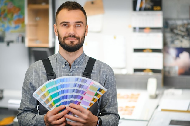 Tipógrafo de pé com amostras de cores na fábrica de impressão
