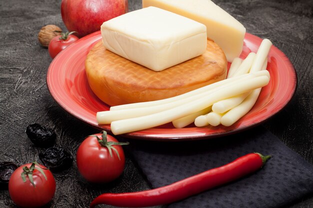 Tipos de varios quesos en un plato rojo.