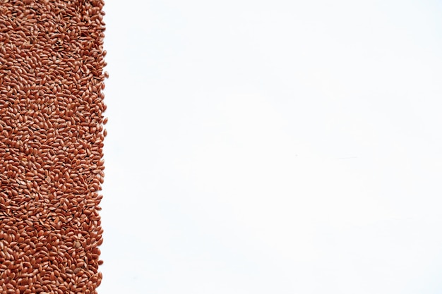 Una tira de semillas de lino marrón sobre un fondo blanco con espacio para copiar
