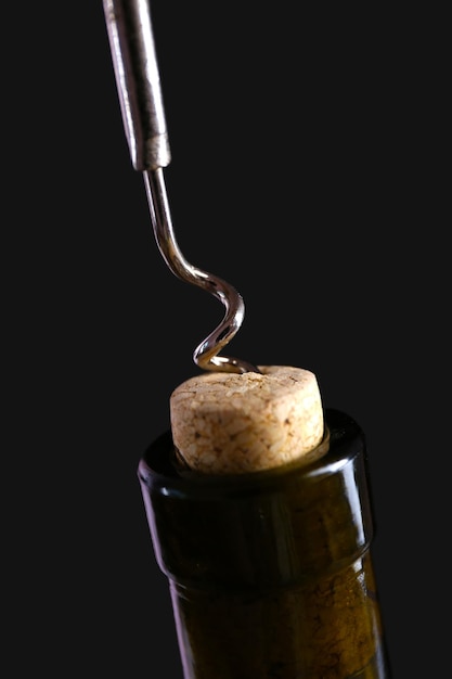 Tirador de corcho y botella de vino sobre un fondo negro