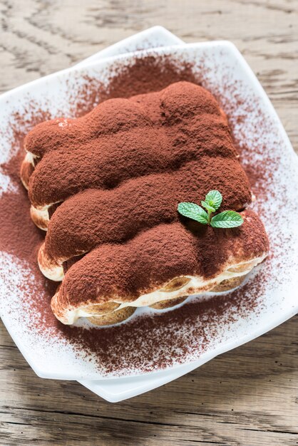 Tiramisu auf dem Teller auf dem Holztisch