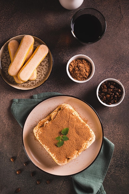 Tiramisu bolo feito de biscoitos creme delicado e café em um prato e vista vertical