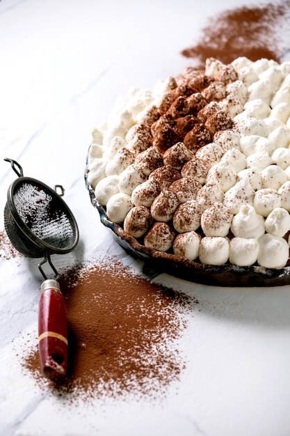 Tiramisú casero sin gluten postre italiano tradicional espolvoreado con cacao en polvo sobre una mesa de mármol blanco