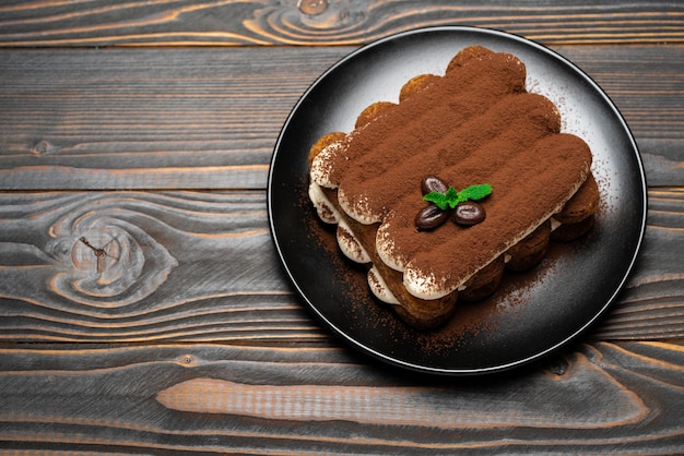 Tiramisú clásico postre en plato de cerámica sobre fondo de madera