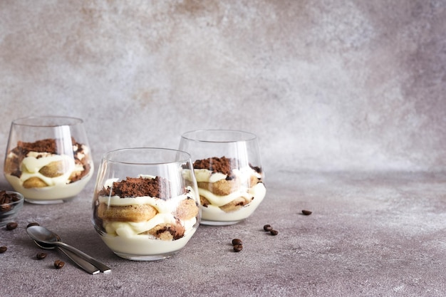 Tiramisú clásico con savoiardi en un vaso sobre un fondo de piedra marrón