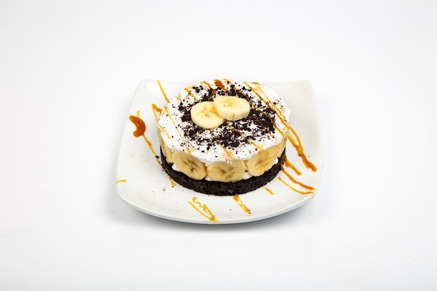 Tiramisu com fundo branco de biscoito, banana e calda de caramelo
