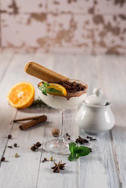 Tiramisu de sobremesa doce em vidro no fundo branco de madeira