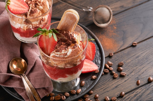 Tiramisú de fresa Tiramisú de postre tradicional italiano en vidrio con fresas frescas y hojas de menta sobre fondo de mesa oscura de madera vieja Espacio de copia Fondo de alimentos