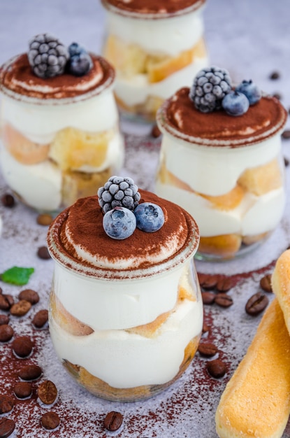 Tiramisú gourmet italiano en vasos espolvoreados con cacao y decorados con bayas congeladas