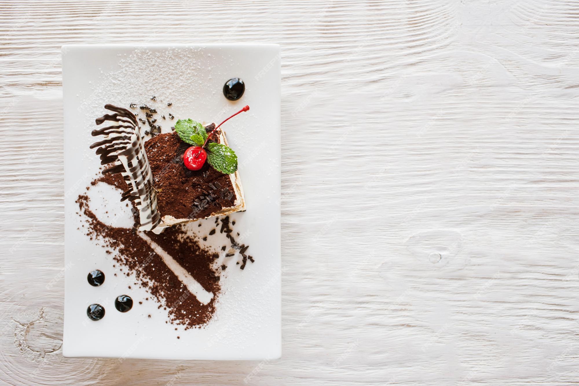 Tiramisú en un plato blanco con decoración de cereza chocolate menta postre dulce que se sirve en restaurante libre cerca de la vista superior | Foto Premium