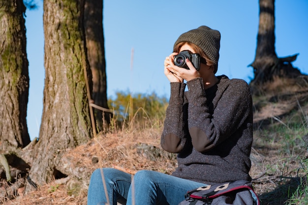 Tirando uma foto com uma velha câmera analógica na floresta. alpinista usando uma câmera em uma bela cena da natureza em um dia ensolarado