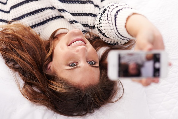 Tirando uma foto Foto recortada de uma bela jovem tirando uma selfie em casa