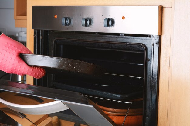 Foto tirar a bandeja assada do forno com luvas de cozinha