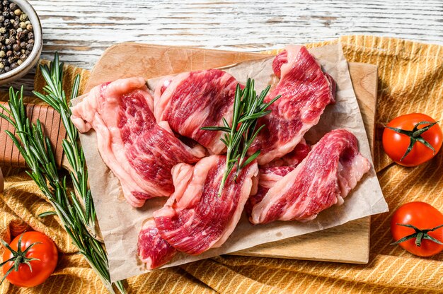 Tiras de carne marmolada, filete rápido en tabla de cortar. Fondo de madera blanca Vista superior