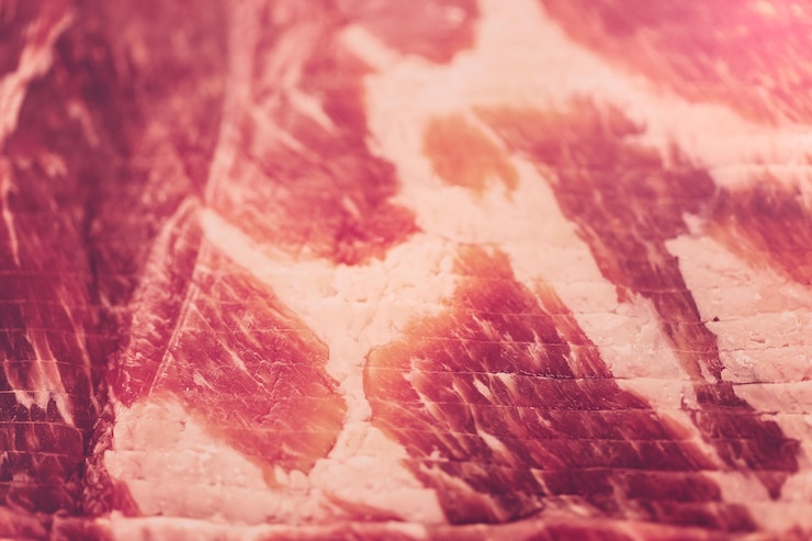 Foto tiras de bacon cru em um fundo branco.