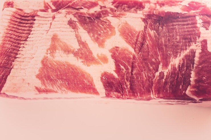 Foto tiras de bacon cru em um fundo branco.
