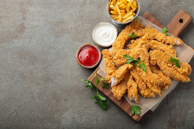 Tiras de frango à milanesa com dois tipos de molhos.