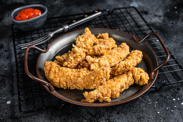 Tiras de pollo crujiente con salsa de tomate Fondo negro Vista superior