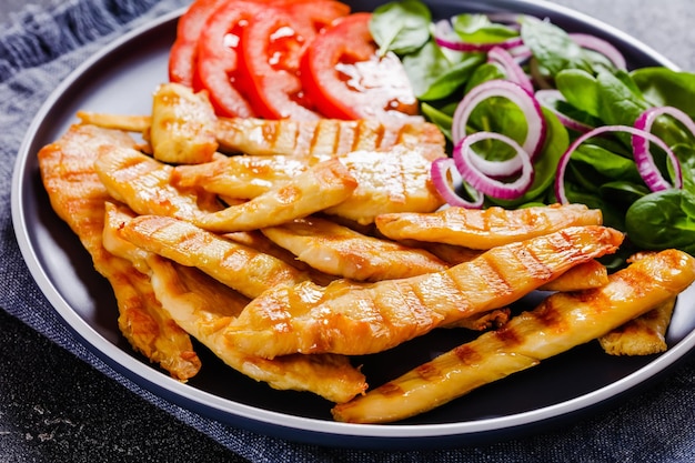 Tiras de pollo a la parrilla en un plato con verduras