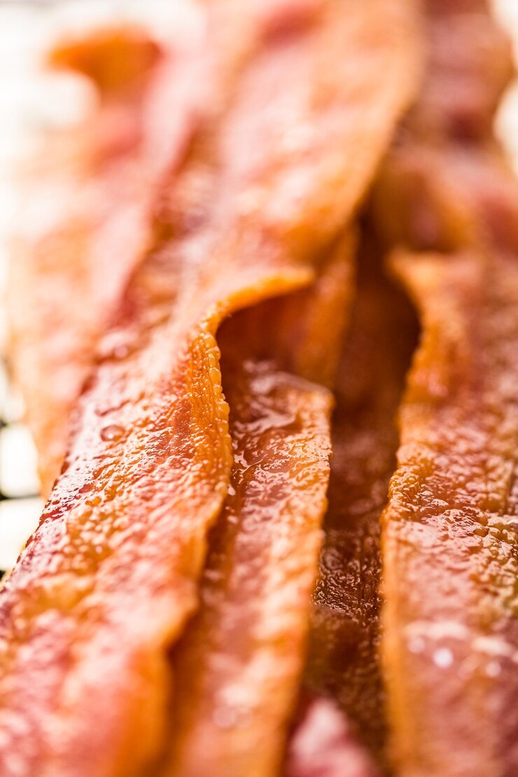 Foto tiras de tocino cocidas en una bandeja para hornear.